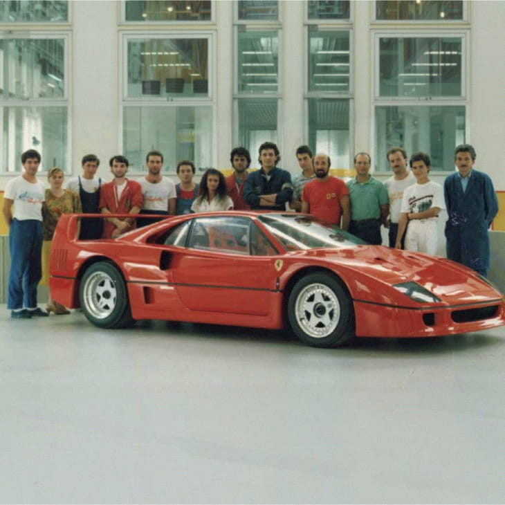 Foto di gruppo del team dell'Officina Michelotto con la Ferrari F40 rossa in officina